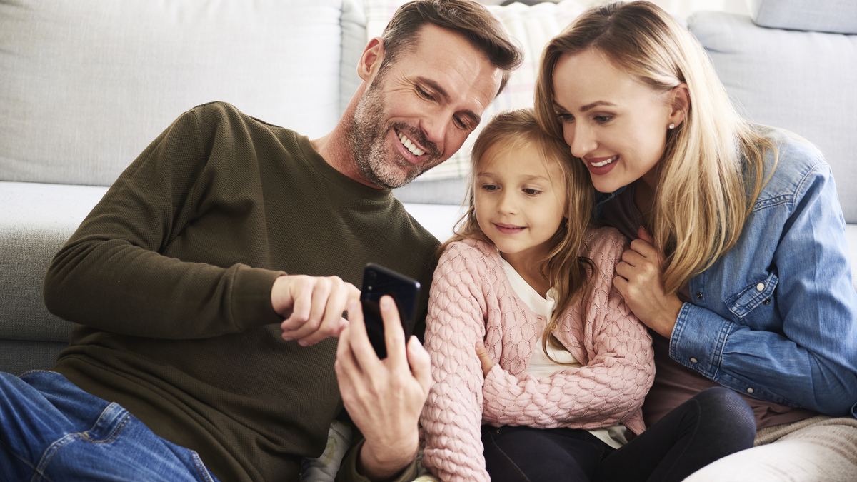 Family sitting around table sharing photos across iPhones and iPads wirelessly